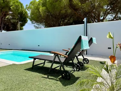 a chair and a picnic table next to a swimming pool at Casa Lumier in Chiclana de la Frontera