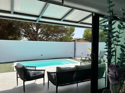 a patio with a swimming pool and chairs and a table at Casa Lumier in Chiclana de la Frontera