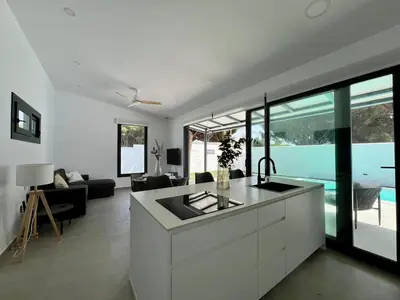 a kitchen and living room with a view of a pool at Casa Lumier in Chiclana de la Frontera