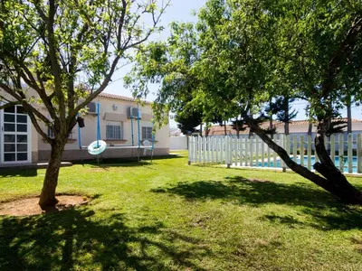 a yard with two trees in front of a building at Villa Los Veleros 15119 in Chiclana de la Frontera