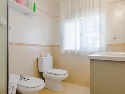 a white bathroom with a toilet and a sink at Villa Los Veleros 15119 in Chiclana de la Frontera