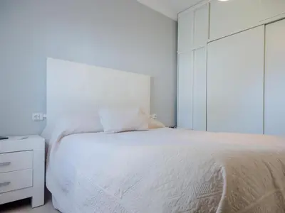 a bedroom with a white bed and a white cabinet at Villa Los Veleros 15119 in Chiclana de la Frontera