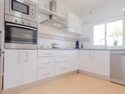 a white kitchen with white cabinets and a window at Villa Los Veleros 15119 in Chiclana de la Frontera