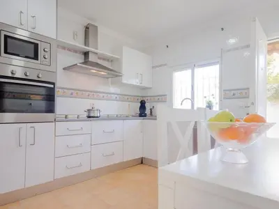 a white kitchen with a bowl of fruit on a counter at Villa Los Veleros 15119 in Chiclana de la Frontera