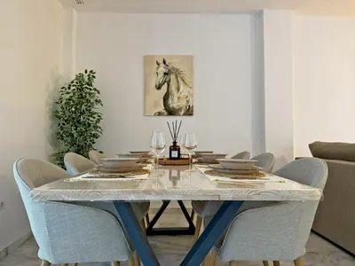 a dining room table with chairs and a painting of a horse at Apartamento Castellanos - Ole Solutions in Jerez de la Frontera