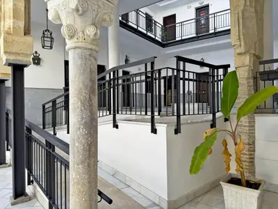 a staircase with black railings and a column with a plant at Apartamento Castellanos - Ole Solutions in Jerez de la Frontera