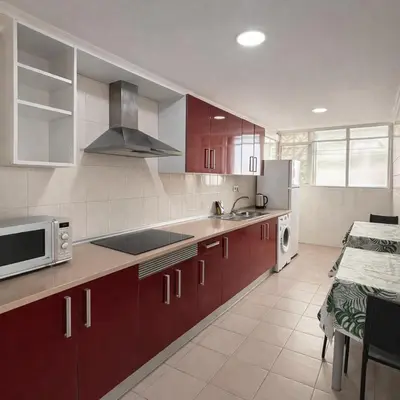 a large kitchen with red cabinets and a microwave at BARLOVENTO Family Home by Cadiz4Rentals in Cádiz