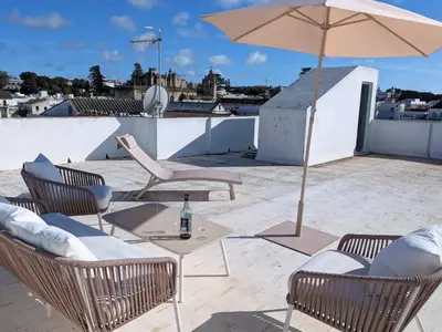 a patio with a table and chairs and an umbrella at Molly's Sunny Penthouse in Sanlúcar de Barrameda