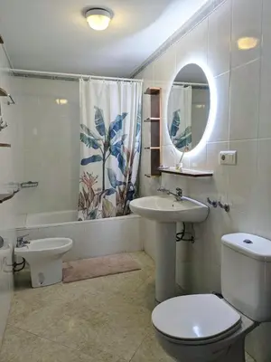 a bathroom with a toilet and a sink and a mirror at Molly's Sunny Penthouse in Sanlúcar de Barrameda
