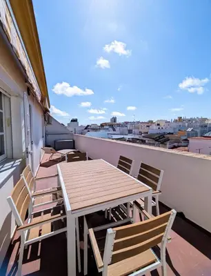 a table and chairs on a balcony with a view at Molly's Sunny Penthouse in Sanlúcar de Barrameda