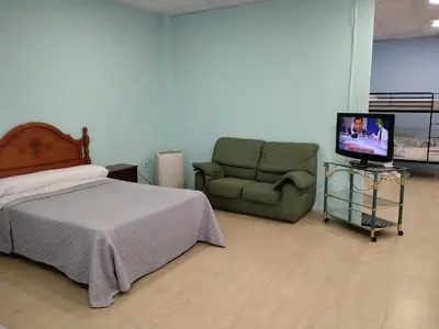 a bedroom with a bed and a couch and a television at Cádiz bahía in Cádiz