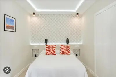 a bedroom with a white bed with two red pillows at Loft El Estudio in Arcos de la Frontera
