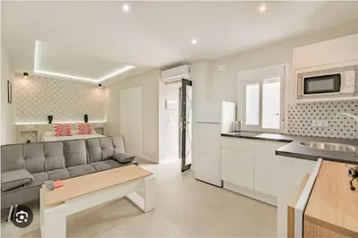 a kitchen and living room with a gray couch in a room at Loft El Estudio in Arcos de la Frontera
