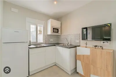a kitchen with white cabinets and a sink and a refrigerator at Loft El Estudio in Arcos de la Frontera