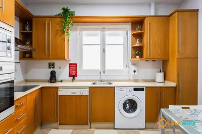 a kitchen with wooden cabinets and a washing machine at The Hideaway of Cádiz by livework in Cádiz