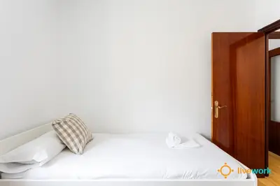 a bedroom with a white bed with a wooden cabinet at The Hideaway of Cádiz by livework in Cádiz