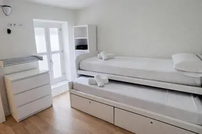 a white bedroom with a bed and a window at Rosario by Gades Gestión in Cádiz