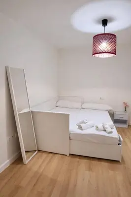a white bedroom with a bed and a mirror at Rosario by Gades Gestión in Cádiz