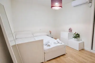 a small white bedroom with a bed and a mirror at Rosario by Gades Gestión in Cádiz
