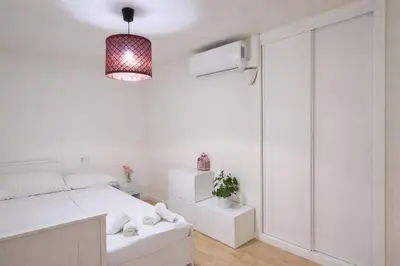 a white bedroom with a bed and a pendant light at Rosario by Gades Gestión in Cádiz