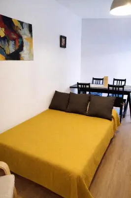 a bedroom with a yellow bed with a table and chairs at SOTAVENTO Apartment by Cadiz4Rentals in Cádiz