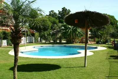 a swimming pool with an umbrella next to a palm tree at Casa Costa Atlantica in Costa Ballena