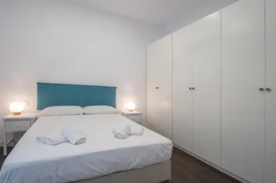 a white bedroom with a large bed with two white cabinets at Zambra en Cádiz in Cádiz