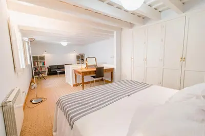 a white bedroom with a bed and a desk at Duplex de la Botánica de Cádiz in Cádiz