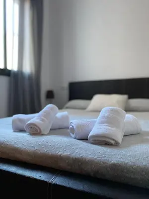 three rolled towels sitting on top of a bed at Piso en el Centro de Sanlucar in Sanlúcar de Barrameda