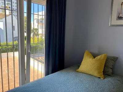 a bed with a yellow pillow in front of a window at Casa Salinera Valdelagrana Cádiz - Playa - Ideal para familias in El Puerto de Santa María