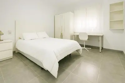 a white bedroom with a white bed and a desk at Apartamento Plaza Falla Caleta in Cádiz