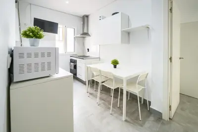 a white kitchen with a white table and chairs at Apartamento Plaza Falla Caleta in Cádiz