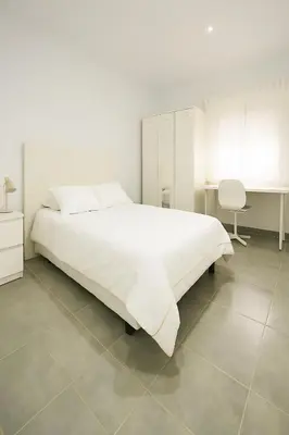 a white bedroom with a large bed and a desk at Apartamento Plaza Falla Caleta in Cádiz