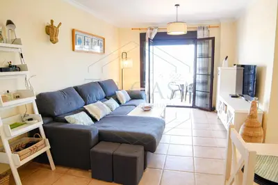 a living room with a blue couch and a kitchen at Ático, El Refugio de Sancti Petri in Novo Sancti Petri
