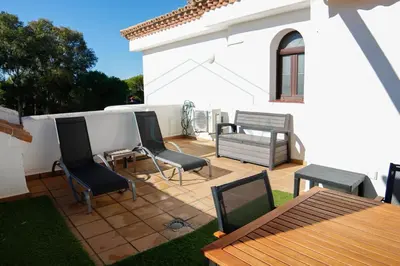 a patio with chairs and a table and a white house at Ático, El Refugio de Sancti Petri in Novo Sancti Petri