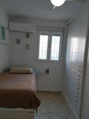 a bedroom with a bed and two windows at Ático en San Fernando in San Fernando