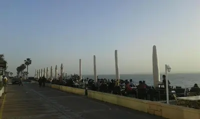 a group of people sitting on a sidewalk near the ocean at Loft El pez blanco in El Puerto de Santa María