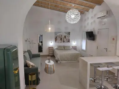a living room with a bed and a kitchen with a table at La corrala de la calle Sol in Jerez de la Frontera