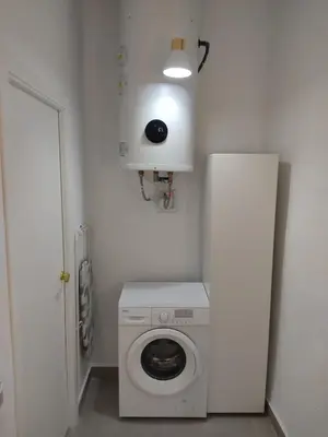 a washer and dryer in a white room with a door at La corrala de la calle Sol in Jerez de la Frontera