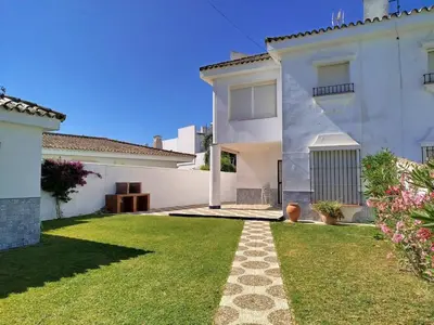 a large white house with a grass yard at Villa Duplex 3 Bedrooms, 400 M to the beach, Pool in Novo Sancti Petri
