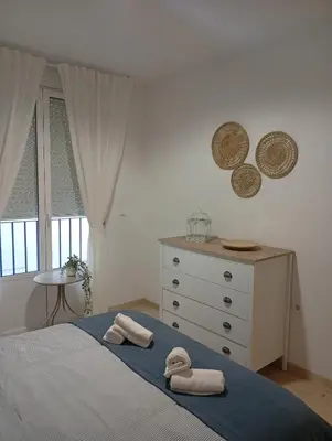 a bedroom with a bed and a dresser and two towels at Tartaneros Playa con Parking in Sanlúcar de Barrameda