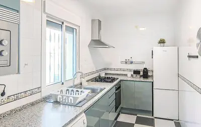 a white kitchen with a sink and a refrigerator at Stunning Home In Chiclana De La Fronter in Novo Sancti Petri