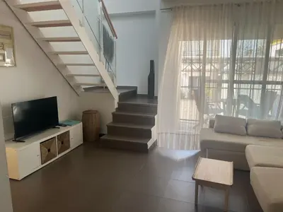 a living room with a couch and a tv and stairs at Apartamento Sanlúcar in Sanlúcar de Barrameda