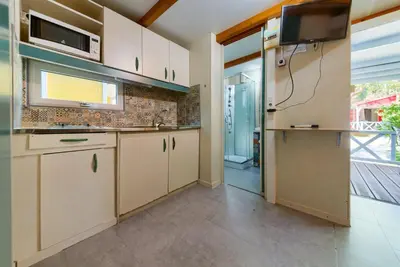 a kitchen with white cabinets and a flat screen tv at Bungalows - Conil Playa in Conil de la Frontera