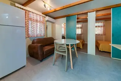 a kitchen and living room with a table and a chair at Bungalows - Conil Playa in Conil de la Frontera
