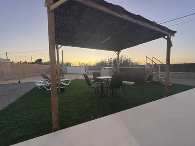 a patio with a table and chairs on the grass at Casa Abuelo Pedro in Conil de la Frontera