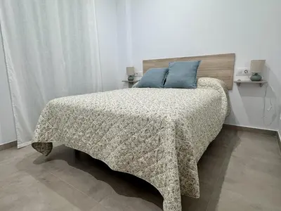 a bedroom with a bed with a blanket and blue pillows at Casa Abuelo Pedro in Conil de la Frontera