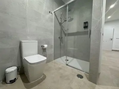 a bathroom with a toilet and a glass shower at Casa Abuelo Pedro in Conil de la Frontera