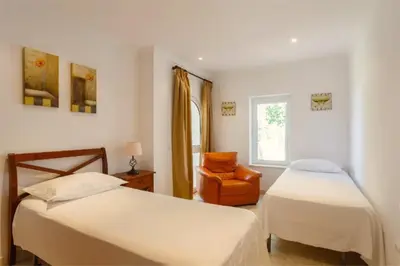 a bedroom with two beds and a chair and a window at Villa 235 by Villamya in Arcos de la Frontera