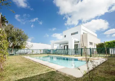 a house with a swimming pool in front of a fence at Villa Puntalejo por Living Cadiz in Conil de la Frontera